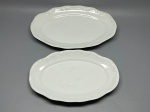 PORCELANA SCHMIDT - Dupla de travessas ovais vintage em porcelana branca da tradicional marca Schmidt, com delicados relevos em estilo barroco/rocaille nas abas e bordas onduladas. Marcadas no verso com o clássico carimbo verde da coroa e o nome Schmidt. Med. 32x22 cm e 28x18 cm. Marcas do tempo e de uso.