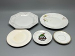 PORCELANA - Conjunto composto por 5 peças de porcelana e louça de tamanhos variados (do maior com 21 cm ao menor com 10 cm), incluindo um prato octogonal decorado com motivos florais em relevo e friso, um prato com delicado arranjo floral policromado nas abas e bordas onduladas, e três peças menores (prazos/pires de apoio), destacando-se uma peça comemorativa personalizada com o brasão e tema da Schützenfest de Jaraguá do Sul (Santa Catarina) e outra com friso dourado. Peças vintage com desgastes normais do tempo e uso.