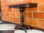 MOBILIÁRIO - Mesa de jogo / apoio dobrável em madeira escura com tampo articulado/rebatível, coluna central torneada com detalhes abaulados, base recortada com pezinhos estilizados e entalhes decorativos nas laterais. Dimensões aproximadas: 75 cm (altura) x 89 cm (largura) x 84 cm (profundidade aberta) / 42 cm fechada. <br><br>Móveis Usados - Lote de móvel antigo e usado, podendo apresentar marcas de uso e desgaste natural do tempo. Há possibilidade de danos ocultos e ou outras imperfeições. Não há garantia ou possibilidade de devolução após a aquisição. Recomenda-se inspeção prévia.