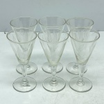 DEMI CRISTAL - Lote com Seis Taças em Demi Cristal Transparente Trabalhado com Lapidação de Folhagens/Ramos - Conjunto composto por seis taças em demi cristal transparente de cálice cônico, haste delicada e base circular plana. O bojo é finamente decorado com lapidação em relevo (fosca) formando motivos que remetem a ramos ou folhas dispostos simetricamente, complementados por finas linhas horizontais gravadas na parte inferior.