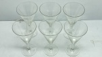 DEMI CRISTAL - Lote com Seis Taças em Demi Cristal Transparente Trabalhado com Lapidação de Folhagens/Ramos - Conjunto composto por seis taças em demi cristal transparente de cálice cônico, haste delicada e base circular plana. O bojo é finamente decorado com lapidação em relevo (fosca) formando motivos que remetem a ramos ou folhas dispostos simetricamente, complementados por finas linhas horizontais gravadas na parte inferior.