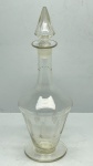 DEMI CRISTAL - Garrafa / Licoreira Antiga em Demi Cristal Transparente com Lapidação de Folhagens e Rolha Lapidada - Elegante garrafa ou licoreira em demi cristal transparente, acompanhada de sua rolha original facetada em formato cônico/piramidal. O corpo apresenta base alargada e pescoço longo, finamente decorado na parte inferior com lapidação em relevo (fosca) formando motivos de ramos ou folhas simétricas e linhas horizontais gravadas.