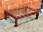 MOBILIÁRIO - Bela mesa de centro em mogno maciço, com tampo de vidro, dotada de design clean e atemporal. Excelente estado. Med. 37x100x72 cm.