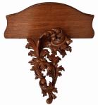 PEANHA EM MADEIRA  Rica peanha sacra em alto-relevo, com volutas e folhagens de inspiração Barroca/Rococó, apresentando belo trabalho escultórico e acabamento em madeira de tonalidade castanho-avermelhada. Medidas: 43 x 30 x 22 cm.