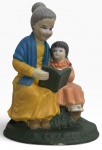 SANTANNA  ITALIAN STYLE  Escultura figurativa em cerâmica policromada, representando mãe e duas crianças em cena familiar, com pintura manual em tonalidades vivas e detalhes delicados. Marca no verso SANTANNA  ITALIAN STYLE. Peça decorativa de inspiração italiana, apresentando sinais de uso e desgaste compatíveis com a idade. Mede 14cm x 11cm.