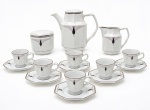 ART DÉCO  elegante conjunto em porcelana branca esmaltada, de linhas geométricas e formas facetadas, decorado com motivos estilizados em tons de malva e preto, com delicados filetes em prata. Composto por bule, leiteira, açucareiro e 6 xícaras com respectivos pires octogonais. Marca SCHMIDT. Exemplar de estética refinada, característica do período Art Déco. Medida do maior 19 x 16 cm.