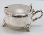 EBERLE- Uma (1) queijeira ou farinheira em metal espessurado a prata, tampa com abertura basculante e articulada, pega e pés no formato de concha. Med. 9,5 cm.