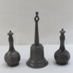 Três (03) peças em pewter de cunho religioso sendo; dois recipientes para óleo cinzelados com guirlandas e um sino. Med. recipiente 15 cm alt, sino 22 cm alt. Recipientes com uma mossa cada.