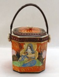 JAPAN- Antiga biscoiteira de coleçõo em porcelana japonesa na cor verde pintada á mão decorada com figuras de signatários na cor laranja em alto relevo no estilo Satsuma, alça em palha trançada. Marcado na base com antiga marca de exportação Séc. XX letra H. Med. 15 x 17 cm.