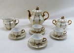 MAUÁ- Gracioso conjunto para café em antiga porcelana branca iridiscente moldado na pasta, decorado com ramos em farta douração pintados a mão, composto; Bule ( 15 cm alt) cremeira, açucareiro e quatro xícaras com pires. Mínimo desgaste na douração (VIDE FOTOS).