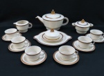 VISTA ALEGRE- Conjunto para chá Art Deco em porcelana portuguesa na cor marfim, decorado com faixas florais em dourado, composto : Grande bule para chá ( 16 cm alt), cremeira, açucareiro, mantegueira e seis xícaras para chá com pires e prato para bolo ( 23 cm diâmetro). Maracado na base. 11 peças.