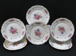 KPM MADE IN POLAND- Seis (06) pratos rasos em porcelana polonesa, manufatura KPM. moldada na pasta em guirlandas borda com rosáceas e friso dourado. Med. 24 cm diâmetro.