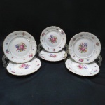 KPM MADE IN POLAND- Seis (06) pratos sobremesa em porcelana polonesa, manufatura KPM. moldada na pasta em guirlandas borda com rosáceas e friso dourado. Med. 19 cm diâmetro.