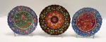KUTAHYA/IZNIK - Três (03) pratos decorativos em cerâmica turca, pintados a mão com motivos florais vitrificadas com detalhes em alto relevo. Med. 7,5 cm diâmetro.