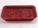 Antiga bandeja retangular em laca chinesa, ricamente ornada em alto relevo, bordas florais, ao centro dois dragões disputando a pérola. Selado com ideograma na base. Med. 5 x 31 x 18,5 cm.