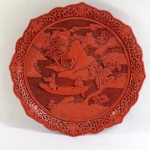 Medalhão em laca chinesa, ricamente ornada em alto relevo, bordas em guirlandas com florais, ao centro paisagem lacustre com pagodes, arbustos e figuras femininas com barco. Med.3 x 25 cm diâmetro.