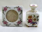 Lote com duas (02) peças em porcelana, sendo; um perfumeiro decorado com florais e farta douração, um porta retrato quadrado. Med. 14 cm altura- 36 x 34 x 28 cm.