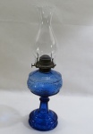 Lampião antigo à querosene em vidro "Esberard" na cor azul e manga alta em vidro translúcido., haste facetada, bojo soprado e moldado. Med. 45 cm altura.
