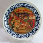 TALAVERA DE PUEBLA- Medalhão em cerâmica Mexicana vitrificada, com técnica de popotillo retratando uma paisagem de Vila Colonial, borda com guirlandas em relevo na cor azul cobalto. Med. 31 cm diâmetro.
