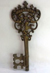 Grande chave decorativa em metal dourado fundido e lavrado , fabricado a partir de meados do Séc. XX estilo Regency, destaca-se pela coroa superior com arabescos vazados e figura central de um leão Heráldico. Med. 42 x 17 cm. Peso 2,6 Kg.