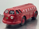 Miniatura die-cast em formato de mealheiro do camião cisterna aerodinâmico Texaco "1934 Diamond T Doodlebug", produzido pela The Ertl Company para a Kipp Bros., Inc. (Officially Licensed Product, 1994, Edition #11). Apresenta carroçaria em tom vermelho vivo com inscrições "TEXACO" nas laterais e frente, logótipos circulares da marca e bomba de combustível ilustrada, ranhura superior para moedas e portinhola inferior de fecho com chave, jantes vermelhas com pneus pretos e chassi inferior detalhado em plástico preto com inscrições de fabrico gravadas. Medidas: 06 x 20 x 06 cm. Com marcas de tempo de uso.