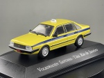 Miniatura die-cast do sedan Volkswagen Santana configurado como táxi do Rio de Janeiro ("Veículos de Serviço do Brasil"), com pintura em amarelo e faixa lateral azul. Apresenta letreiro "TAXI" no tejadilho, jantes raiada-esportivas prateadas, para-choques pretos com frisos cromados, placas identificativas e base expositora personalizada. Medidas: 03 x 09 x 03 cm. Com marcas de tempo de uso.