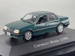Miniatura die-cast do sedan Chevrolet Monza (1988) na cor verde-escuro, pertencente à coleção de veículos clássicos brasileiros. Apresenta detalhes fiéis do modelo de quatro portas, incluindo grelha frontal preta com emblema, para-choques e frisos laterais pretos com detalhe cromado, jantes de liga leve prateadas, placas identificativas "CHEVROLET MONZA" e base expositora gravada com a identificação "CHEVROLET MONZA (1988)". Medidas: 03 x 07 x 03 cm. Com marcas de tempo de uso.