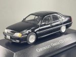 Miniatura colecionável em die-cast (metal com detalhes em plástico) referente ao sedan executivo Chevrolet Omega CD do ano de 1992. Apresenta pintura na cor preta. Destaca-se pelo detalhamento das linhas aerodinâmicas do veículo, incluindo teto de abrir demarcado, frisos laterais com debrum cromado, maçanetas, retrovisores, lanternas traseiras encarnadas em acrílico, ponteira dupla de escape e placa identificativa "Chevrolet Omega CD" acompanhada dos emblemas "Omega 3.0" e "Chevrolet" na traseira. Acompanha jantes raiadas estilo favo de mel cromadas. Encontra-se fixado sobre base expositora rígida na cor preta.   Estado de Conservação:A peça apresenta avaria visível na roda traseira esquerda, onde o pneu de borracha se encontra descolado/desencaixado da jante cromada. A estrutura de metal e a pintura preta encontram-se em bom estado geral, assim como os vidros acrílicos e a base expositora.   Medidas: 3 cm (altura)  11 cm (comprimento)  3 cm (largura).