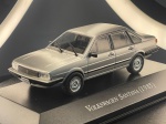 Miniatura colecionável em die-cast (metal com partes em plástico) referente ao icônico sedan de luxo Volkswagen Santana do ano de 1985. Possui pintura em tom cinza prata metalizado. Destaca-se pelo fiel detalhamento da carroçaria de quatro portas, incluindo para-choques envolventes com frisos, grelha frontal com o emblema da marca, faróis dianteiros retangulares transparentes, limpadores de para-brisa aplicados, retrovisores, maçanetas destacadas e frisos laterais de proteção. Equipado com rodas raiadas cromadas e pneus em borracha. Encontra-se fixado sobre base expositora rígida na cor preta, com a identificação do modelo gravada em letras prateadas na frente.   Item em excelente estado de conservação, com pintura brilhante, estrutura íntegra, sem faltas ou avarias. Vidros acrílicos translúcidos e preservados. A base expositora apresenta-se impecável.   Medidas: 3 cm (altura)  10 cm (comprimento)  3 cm (largura).