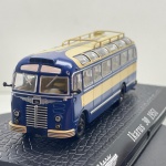 Miniatura colecionável em die-cast (metal com pormenores em plástico) referente ao clássico autocarro húngaro Ikarus 30 do ano de 1951. Apresenta pintura bicolor em azul-escuro na secção principal e creme no teto e faixa lateral. Destaca-se pelo elevado detalhamento de época, incluindo a imponente grelha frontal cromada com o emblema "Ikarus", faróis circulares dianteiros com luzes auxiliares, para-brisas dividido com limpadores em miniatura, espelhos retrovisores pretos destacados, janelas de iluminação panorâmicas no teto com acabamento translúcido, bagageiro superior vazado na cor creme e para-choques ranhurados. Encontra-se fixado sobre base expositora rígida na cor preta com textura a simular pavimento em paralelepípedos, com a identificação do modelo "Ikarus 30 1951" gravada em letras brancas acompanhada pelo logótipo da marca.   Item em excelente estado geral de conservação, com pintura brilhante, estrutura totalmente íntegra e sem faltas. Vidros acrílicos translúcidos e base expositora em perfeito estado.   Medidas: 3 cm (altura)  11 cm (comprimento)  3 cm (largura).