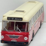 Miniatura die-cast em escala 1/43 do autocarro Büssing Senator 12D. Apresenta pintura bicolor em vermelho e creme, letreiro frontal e traseiro "51 Bf. Altona", matrícula "HH-XT 406", inscrições e logótipos Büssing, publicidade lateral "AEG LAVAMAT" e interior detalhado. Com marcas de tempo de uso.
