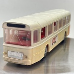 Miniatura clássica do autocarro francês Saviem SC 10 U da marca Norev, com carroçaria em tons de bege e apontamentos em laranja. Possui inscrição "SAVIEM" na dianteira, logótipos e detalhes traseiros "RN", interior detalhado em vermelho e mecanismo de abertura de portas acionado por patilha inferior. O tamanho aproximado é de 5 cm  15 cm  5 cm. Com marcas de tempo de uso.