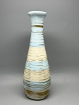 Vaso em cerâmica de forma alongada, corpo cônico alargado na base e gargalo estreito com boca evazada. Superfície decorada com pintura em faixas horizontais nas cores azul claro, creme e dourado/ocre, aplicadas com pinceladas texturizadas que deixam o fundo à vista, criando efeito de estrias. Interior sem cobertura de esmalte, em tom bege. Apresenta trinca na borda da boca, visível nas imagens. Sem marcas ou assinaturas identificadas. Alt. 32 cm. floreira, jarra, peça em barro, vaso de piso, recipiente cerâmico, peça decorativa
