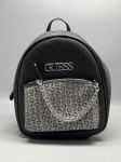 Mochila feminina da marca Guess, confeccionada em material sintético texturizado na cor preta. Apresenta estampa de monograma com iniciais "G" em tom sobre tom na parte frontal e lateral. Bolso frontal com zíper, revestido em tecido jacquard cinza com monograma contrastante, decorado com corrente metálica na cor prateada. Logotipo da marca em metal prateado aplicado na frente. Alças de costas reguláveis e alça de mão superior. Fechamento principal por zíper. Ferragens em metal na cor prateada. Estado de conservação aparentemente bom, sem sinais visíveis de uso nas imagens. backpack, bolsa de costas, sacola, bag, logotipo, brandão, logo, metal prateado, ferragens, estampado
