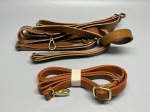 Lote composto por múltiplas alças para bolsa em material sintético na cor caramelo/tan. As peças apresentam acabamento costurado nas bordas e ferragens metálicas em tom dourado envelhecido e dourado polido, incluindo mosquetões, argolas e fivelas reguladoras. Identificam-se dois grupos distintos: um conjunto maior com várias alças de diferentes comprimentos, incluindo uma extremidade em camurça sintética, e uma alça enrolada e presa por fita de papel, aparentemente sem uso. Estado de conservação aparentemente bom. Marca não identificada nas imagens. correia, tira, shoulder strap, bandoleira, ombreira, arreio de bolsa