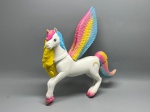 Boneco representando unicórnio alado (alicórnio) em plástico rígido, corpo na cor branca com crina moldada nas cores amarelo, rosa e azul. Chifre dourado na fronte, olhos pintados com cílios. Asas abertas com degradê nas cores rosa, amarelo e azul, com detalhamento de penas em relevo. Cauda multicolorida. Cascos com acabamento em rosa. Estampa de arco-íris impressa no flanco. Colar ao redor do pescoço com detalhe dourado. Modelagem detalhada com acabamento pintado. Estado de conservação aparentemente bom, sem danos visíveis nas imagens. Fabricante e época não identificados nas imagens. escultura em plástico, boneco, estatueta, pegasus, cavalo alado, toy figure