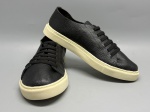 Par de tênis estilo low-top confeccionado em couro com acabamento granulado na cor preta. Modelo de cano baixo com fechamento por cadarço preto plano passado em ilhoses metálicos. Solado em borracha na cor off-white com costura perimetral aparente e textura quadriculada na parte inferior. Biqueira arredondada. Sem marcas ou logotipos visíveis nas imagens. Número não identificado. Estado de conservação aparentemente bom, sem sinais evidentes de uso nas fotos apresentadas. sneaker, calçado casual, sapatênis, footwear, tênis de couro, calçado de amarrar
