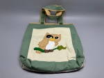 Bolsa tote confeccionada artesanalmente em tecido. Face frontal em tecido verde com painel central em tecido bege claro, decorado com aplique de coruja pousada em galho, executado em patchwork com tecido de bolinhas nas tonalidades marrom, branco e verde. Alças duplas revestidas com tecido de bolinhas bege e verde, fixadas por botões na cor verde-oliva. Face posterior em tecido cru com costura decorativa formando losangos. Bordas e acabamentos em tecido verde. Sem marca identificada. Apresenta sinais de uso. sacola, bag, bolsa de tecido, bolsa bordada, bolsa decorativa, ecobag, corujinha