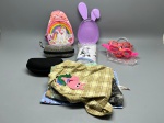 Lote composto por: mochila infantil em tecido rosa com estampa de unicórnio e arco-íris, com alças e fechamento em zíper; prato/bandeja plástica lilás em formato de ovo com orelhas de coelho; dois estojos rígidos para óculos (um cinza estampado e um preto); óculos infantis em armação rosa/laranja em embalagem plástica; itens têxteis variados incluindo panos e bolsas artesanais em tecidos xadrez, poá e pelo sintético, com apliques de personagens em feltro; embalagem fechada com imagem de carrinho de bebê. Estado de conservação a verificar. bolsa escolar, bandeja decorativa, porta-óculos, óculos coloridos, panos artesanais, aplique em feltro, kit infantil