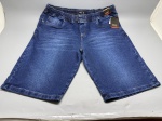 Bermuda masculina em tecido jeans azul médio com efeito estonado. Cós com elástico total e passantes, costura contrastante em tom caramelo. Modelo com bolsos frontais e pequeno bolso auxiliar na lateral esquerda. Etiqueta da marca Nouk Jeans Wear fixada, indicando tamanho 54. Peça nova, com etiqueta original intacta, sem sinais de uso. short, bermudão, calção, denim, short jeans, cós elástico, plus size