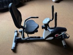 Bicicleta ergométrica do tipo reclinada, marca Kikos. Estrutura em aço pintado nas cores preto e branco. Assento largo acolchoado com encosto, apoios laterais para os braços e pedais com presilha. Console digital central com visor LCD e botões de controle, indicando funções de tempo, velocidade e calorias. Resistência regulável por botão giratório. Estabilizadores dianteiros e traseiros com ponteiras em borracha. Apresenta sinais de uso com marcas de desgaste e poeira. Não foi possível identificar o modelo exato. Estado de conservação a verificar pelo arrematante. bike ergométrica, cicloergômetro reclinado, aparelho de ginástica, equipamento cardiovascular, bicicleta de academia