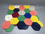Lote composto por dois tapetes confeccionados em crochê, formados por módulos hexagonais unidos, em fio provável de algodão. As peças apresentam composição multicolorida, com módulos nas cores amarelo, azul royal, azul marinho, verde, salmão/rosa, vinho, cinza e branco. A estrutura é formada por fileiras de hexágonos trabalhados individualmente e costurados entre si. Medidas declaradas: 135x66 cm e 95x61 cm. Apresentam sinais de uso. Sem identificação de autoria ou procedência. passadeira, manta, peça têxtil, trabalho manual, patchwork têxtil, carpete artesanal