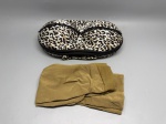 Lote composto por estojo rígido para sutiã, formato anatômico com duas cavidades moldadas, revestido em tecido com estampa animal print nos tons preto, bege e branco, fechamento por zíper preto perimetral com acabamento em renda preta na borda superior. Acompanha peça de vestuário em tecido elástico na cor caramelo/dourado, aparentemente shorts ou cinta modeladora, dobrada. Marca e composição de materiais não identificáveis pelas imagens. Estado de conservação aparente: bom. porta-sutiã, nécessaire, estampa felino, leopardo, modeladora, lingerie