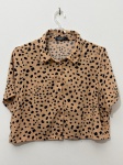 Lote composto por duas camisas cropped femininas, manga curta, gola de alfaiataria e fechamento frontal por botões, tamanho M. A primeira apresenta fundo bege com estampa de manchas pretas no padrão animal print, botões dourados. A segunda possui listras verticais azul-marinho e branco, botões prateados. Ambas com corte reto e comprimento curto. Marca não identificada. Estado de conservação aparente bom, sem sinais visíveis de danos ou manchas nas imagens. blusa, top, camisete, blusão curto, chemise, camisa de botão