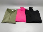Lote composto por três peças de vestuário. A primeira é uma blusa manga longa preta com gola alta franzida, mangas raglan, barra cruzada e punhos canelados, apresenta fiapos e pequenos furos no tecido. A segunda é uma blusa ou body na cor rosa pink, com franzido na gola. A terceira é uma blusa verde militar com zíper frontal parcial e etiqueta interna visível. Marcas, tamanhos e composição dos tecidos não identificados com precisão pelas imagens. Peças apresentam sinais de uso. camiseta, top, moletom, roupa, indumentária, peças de roupa, conjunto de blusas