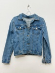 Jaqueta feminina confeccionada em tecido jeans azul médio, corte curto, fechamento frontal por botões metálicos, dois bolsos superiores com aba, gola italiana e punhos com botão. Nas costas, apresenta bordado de aplicação com motivos de olhos e formas triangulares em fios metalizados nas cores dourado, prata, azul marinho e azul claro, com detalhes em miçangas ou pedrarias que conferem textura. A frente não apresenta bordados. Marca não identificada. Tamanho não indicado na imagem. Sem indicação de uso expressivo. casaco denim, jaqueta denim, jaquetão jeans, bordado manual, evil eye, olho turco, miçangas, pedraria, apliquê
