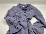 Casaco feminino longo, confeccionado em material de aspecto aveludado, na tonalidade azul acinzentado. Apresenta colarinho com lapela, forro interno em tecido acetinado azul, fechamento frontal com botões na cor vinho, ilhós metálicos na região da cintura com cordão regulável e costuras aparentes em tom claro ao longo do corpo. Os punhos possuem aba com botões. Peça sem tamanho identificado nas imagens. Presença de etiqueta interna não legível nas fotos. Estado de conservação aparente regular, com marcas de uso e amassados. sobretudo, gabardine, overcoat, peça de vestuário, roupa feminina, casacão, abrigo