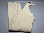 Peça de vestuário em tecido de composição não identificada, coloração bege mesclada. Modelo tipo jardineira ou calça com alças ajustáveis por amarração, apresentando duas alças finas com acabamento em laço nas extremidades. Corte amplo, costura central frontal visível. Peça fotografada dobrada e aberta, evidenciando estrutura da parte superior com decote em V e laterais largas. Sem marca, etiqueta ou identificação visíveis. Apresenta marcas de dobras e uso. Sem outros acessórios ou complementos. macacão, overall, dungaree, calça de alça, roupa de trabalho, indumentária histórica