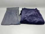 Lote composto por duas calças femininas. A primeira, em tecido liso de composição não identificada, na cor cinza, com cós estruturado e corte reto. A segunda, em tecido aveludado (velour) na cor azul-roxo, com cós em malha canelada e cordão de ajuste na cintura. Ambas se encontram dobradas e apresentam sinais de uso. Tamanho e marca não identificados. Sem etiquetas visíveis nas imagens. Estado de conservação regular. pantalone, legging, calça de moletom, calça jogger, vestuário, indumentária, peça de roupa