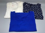 Lote composto por três blusas femininas. A primeira, em tecido leve texturizado na cor off-white, apresenta mangas amplas com babados e abertura com amarração nas costas. A segunda, em malha lisa na cor azul royal, com decote redondo e manga curta. A terceira, em tecido fluido com estampa de pinceladas brancas sobre fundo azul marinho, com manga curta. Peças dobradas, sem marca identificável nas duas primeiras; a terceira apresenta etiqueta parcialmente legível. Estado de conservação aparentemente bom, sem danos visíveis nas imagens. camisa feminina, top, peça do vestuário, indumentária, conjunto de blusas